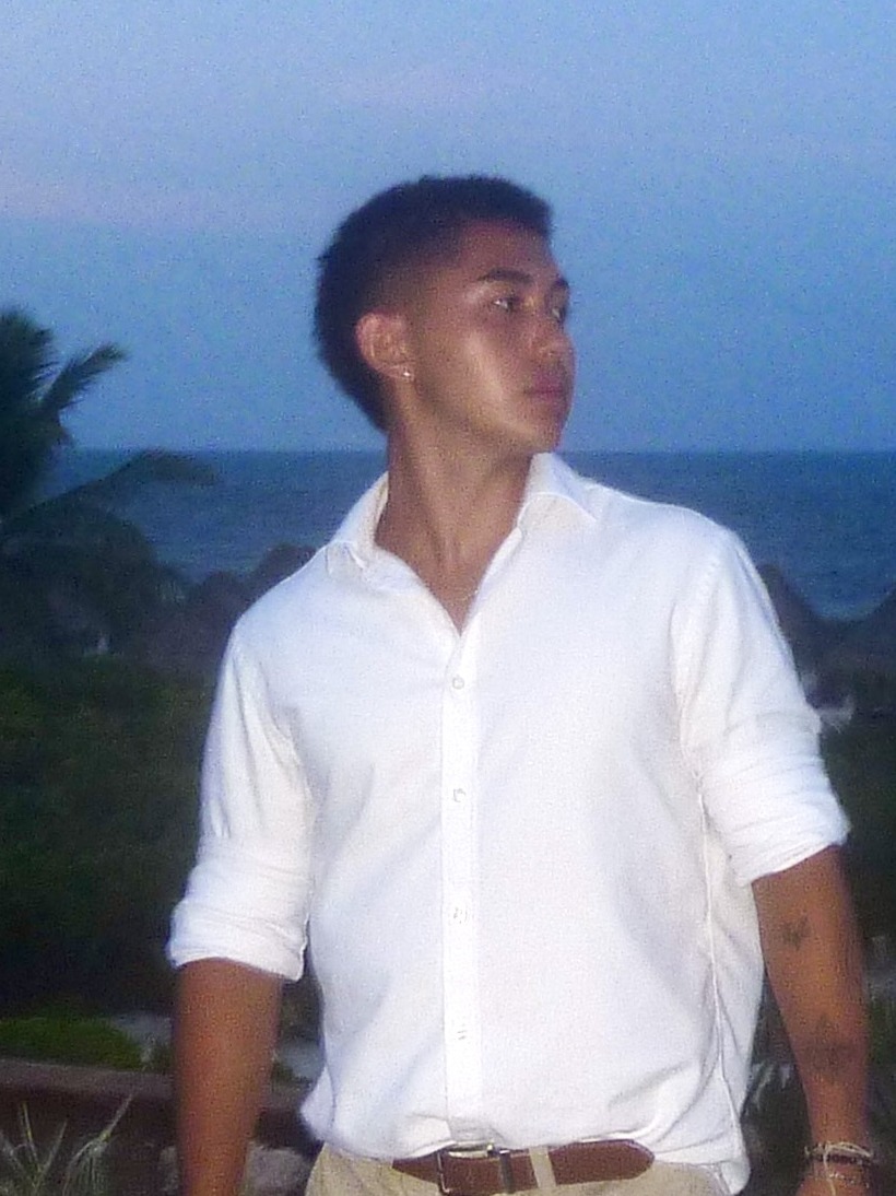 Portrait of Ryan Nakada in a white button-up shirt at dusk by the ocean