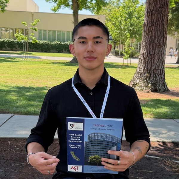 Ryan Nakada holding the Fresno State Social Science Student Symposium program